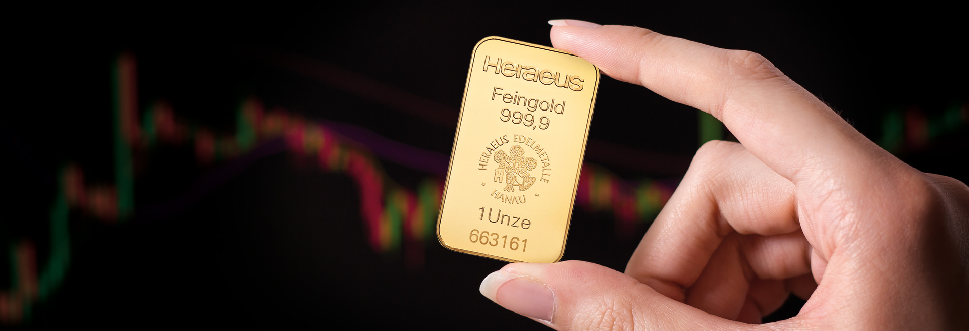 Eine Hand hält einen Goldbarren mit Daumen und Zeigefinger